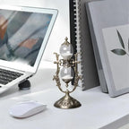 Hourglass sand timer on a desk beside a laptop